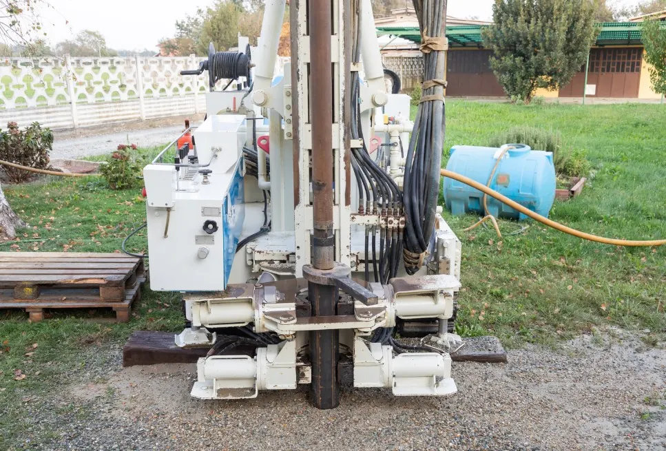 Perforadora compacta ejecutando un pozo en el jardín de una vivienda unifamiliar